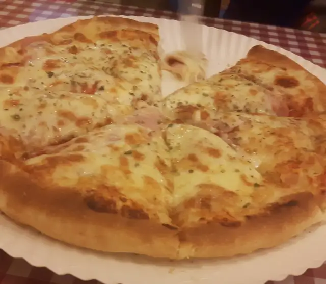 Pizza na grubym cieście, pokrojona, na papierowej tacy