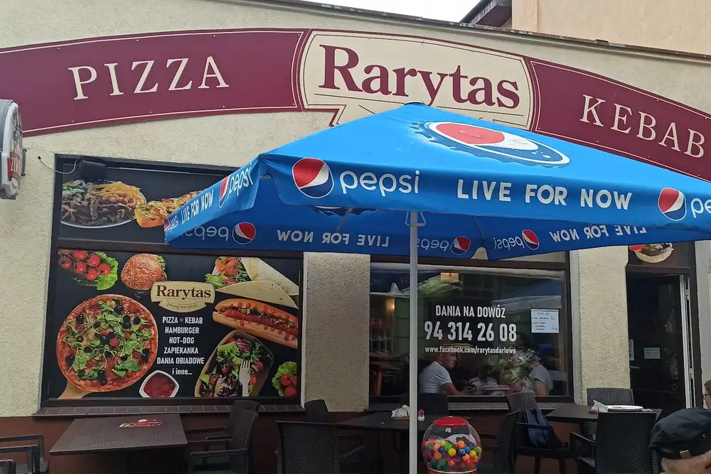 Fasada baru: szyld PIZZA · Rarytas · KEBAB i niebieskie parasole ogródka