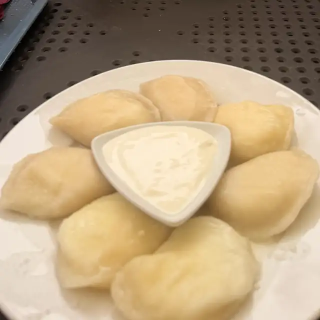 Talerz pierogów ruskich z miseczką śmietany